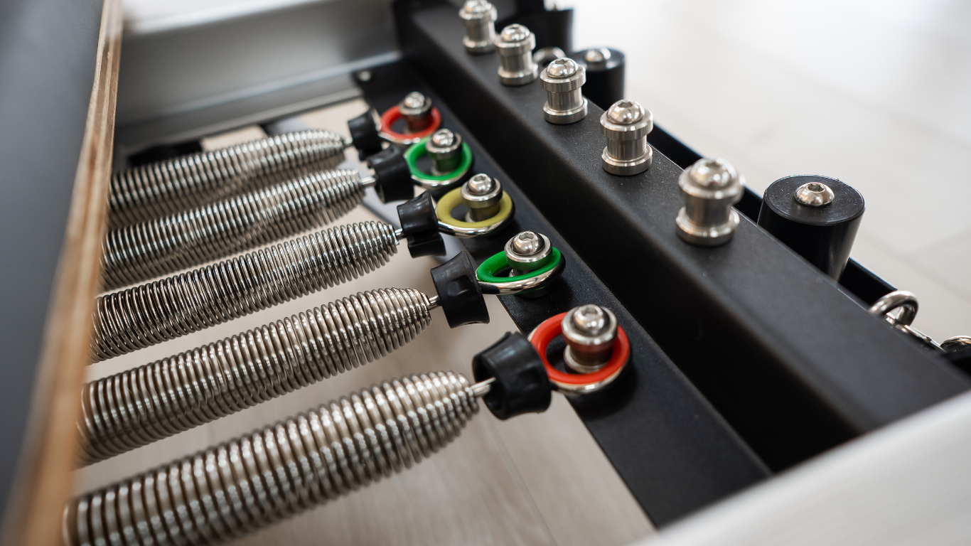 Close-up of Stott Pilates certification materials and reformer spring mechanism illustrating the depth of training required
