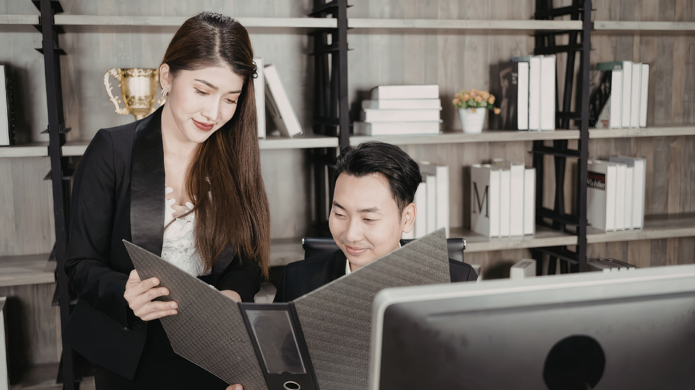 Two business professionals reviewing international due diligence documents before signing a foreign business partner agreement