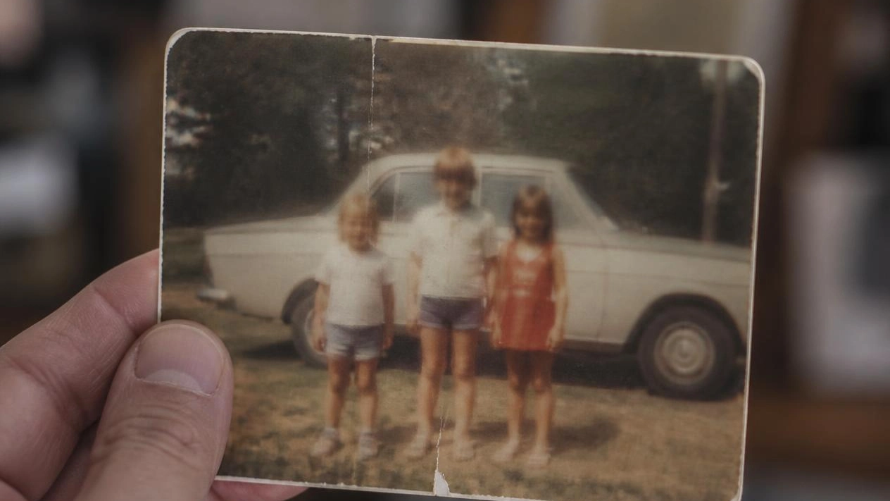 An old family photograph held in an adult hand, representing grief after the death of a sibling in Bergen County, NJ