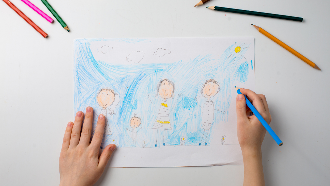 Child's hands drawing a picture of family with colored pencils — processing grief through play