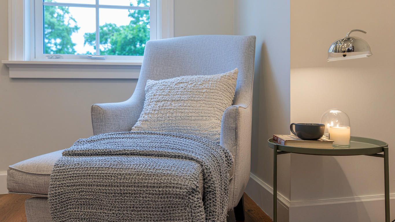 A welcoming therapy room with two armchairs, soft natural light, and a side table with tissues and water for a grief counseling session